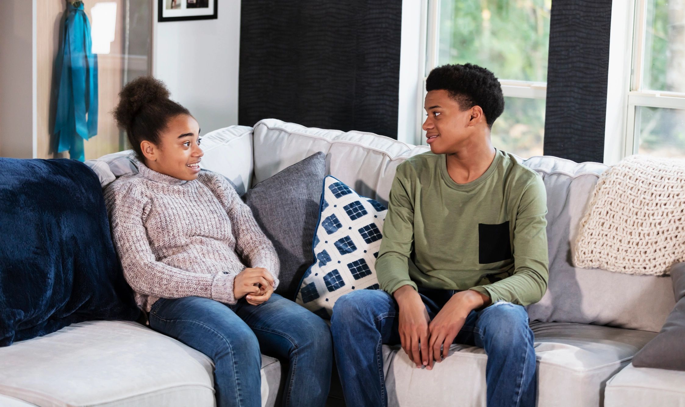 Two teenagers talking together on a sofa